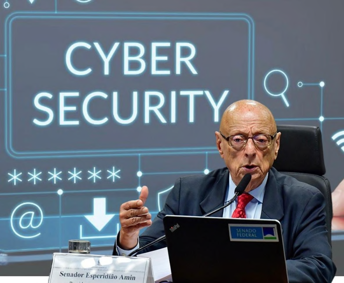 Senator Esperidião Amin speaking into a microphone in front of a cybersecurity screen.
